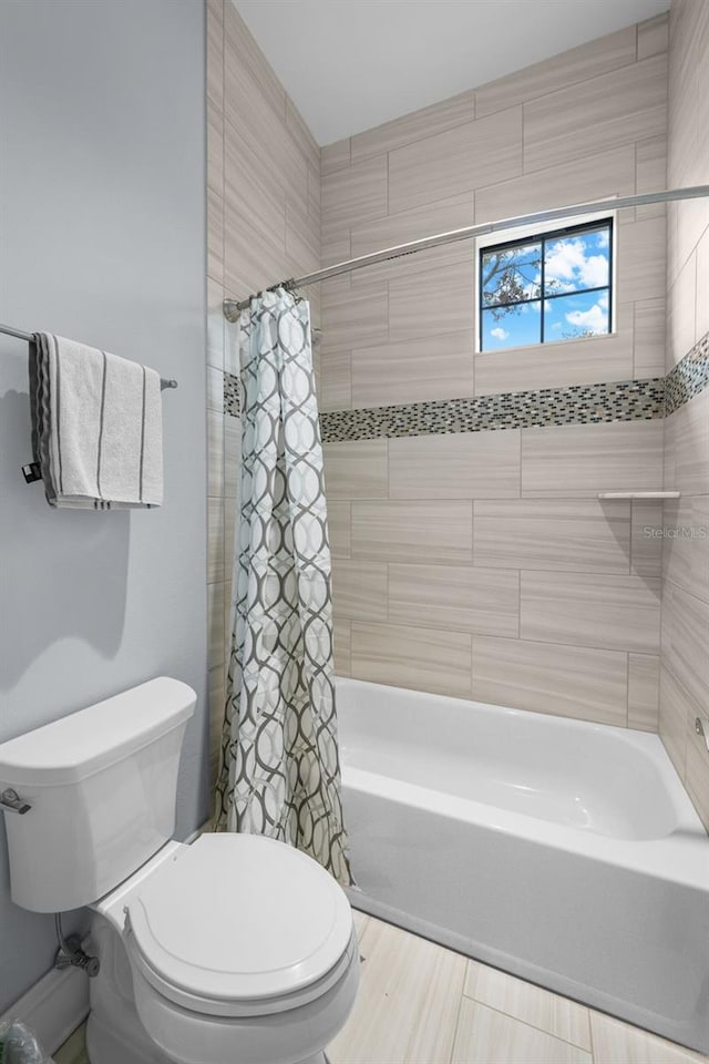 bathroom featuring shower / bathtub combination with curtain and toilet