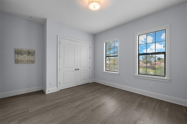 unfurnished bedroom with dark hardwood / wood-style flooring and a closet