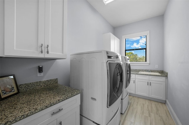 washroom featuring cabinets, washing machine and dryer, and sink