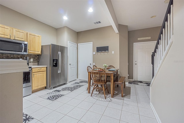 kitchen with light brown cabinetry, appliances with stainless steel finishes, light tile patterned floors, and tasteful backsplash