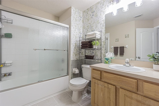 full bathroom with vanity, a textured ceiling, tile patterned flooring, shower / bath combination with glass door, and toilet