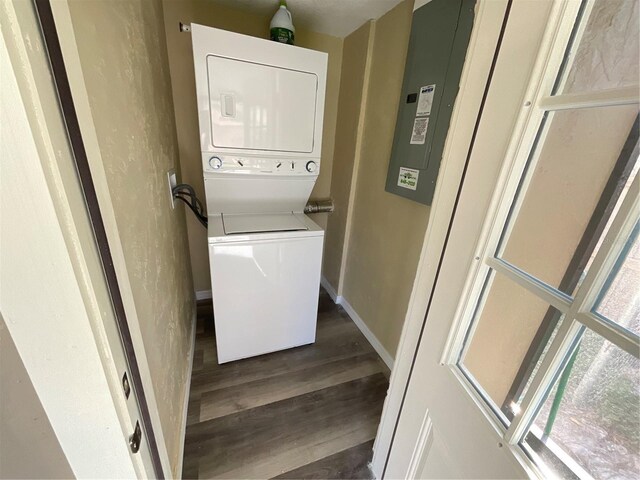 washroom with dark hardwood / wood-style flooring and stacked washing maching and dryer