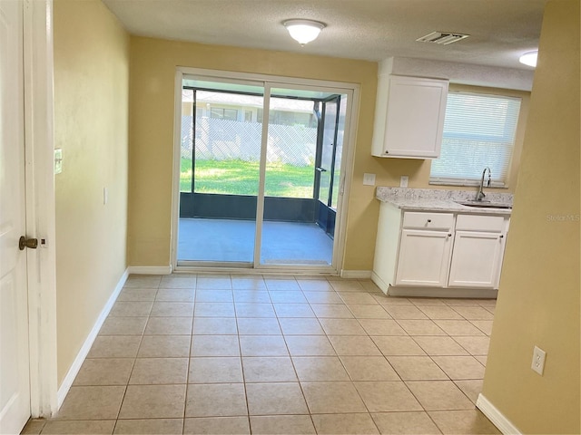 kitchen featuring white cabinets, light tile patterned flooring, sink, and a textured ceiling