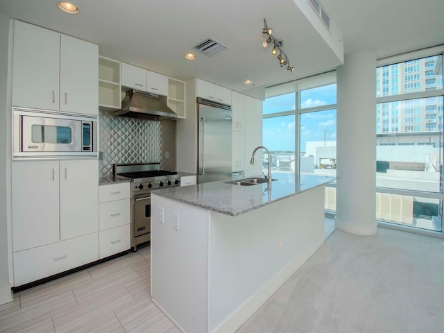 kitchen featuring an island with sink, white cabinetry, built in appliances, and sink