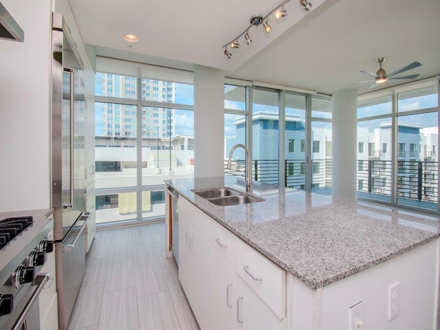 kitchen with white cabinets, a kitchen island with sink, sink, and a healthy amount of sunlight