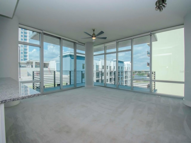 interior space featuring ceiling fan, floor to ceiling windows, and carpet flooring