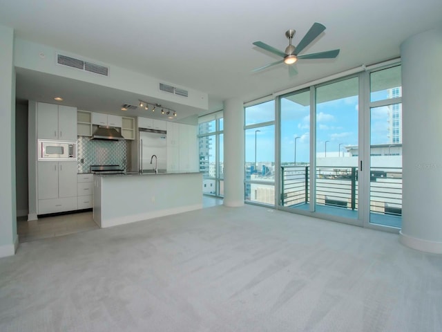 unfurnished living room featuring sink, ceiling fan, and light colored carpet