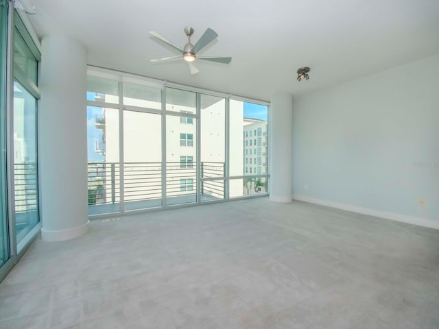 unfurnished room featuring ceiling fan, carpet floors, ornate columns, and expansive windows