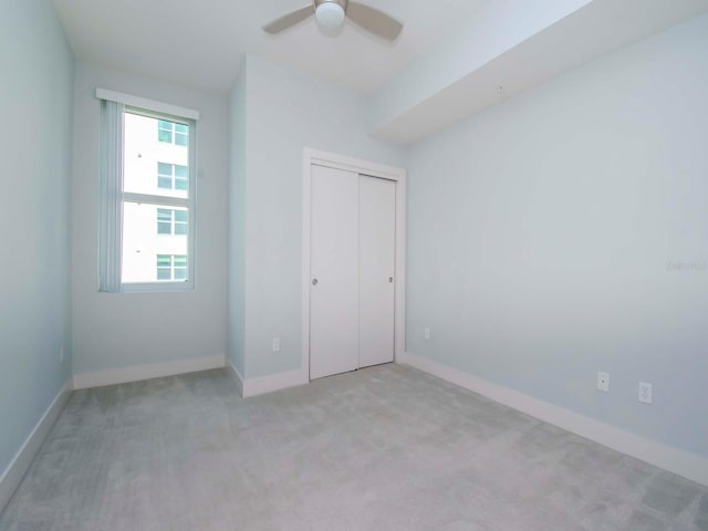 unfurnished bedroom with light carpet, a closet, and ceiling fan