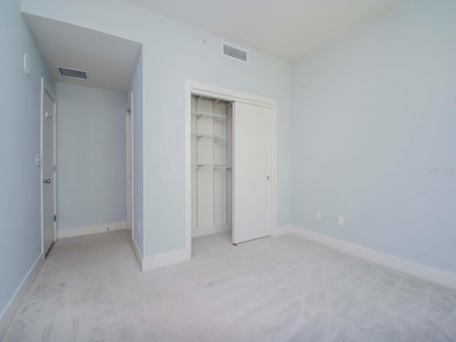 unfurnished bedroom with a closet and light colored carpet