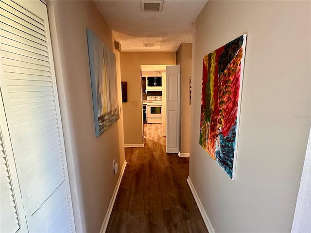 corridor featuring a textured ceiling and dark hardwood / wood-style floors