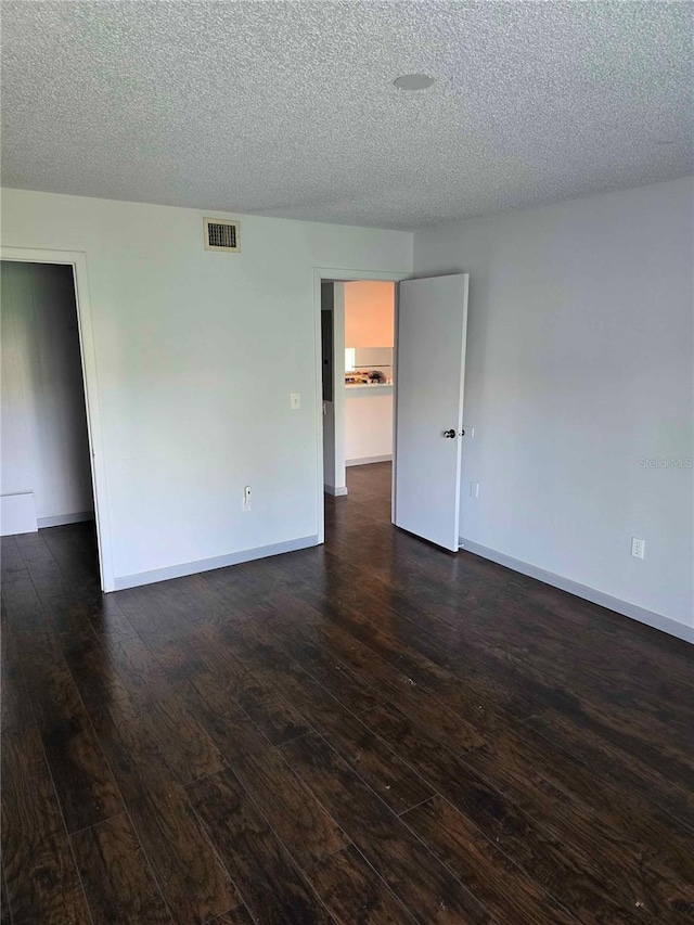 unfurnished room with dark hardwood / wood-style flooring and a textured ceiling