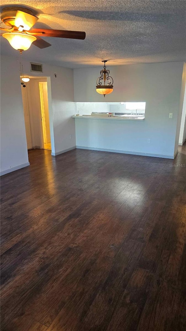 unfurnished room featuring ceiling fan, dark wood-type flooring, and a textured ceiling