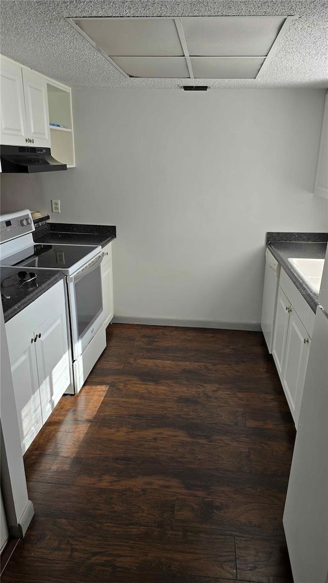 kitchen featuring under cabinet range hood, white appliances, dark countertops, and dark wood finished floors