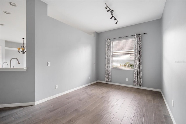 unfurnished room featuring an inviting chandelier and hardwood / wood-style flooring