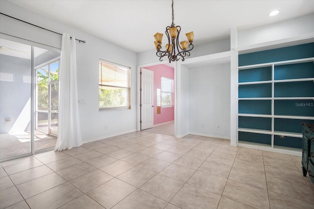 tiled spare room featuring a chandelier and plenty of natural light