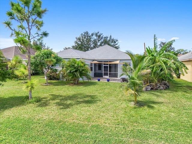 back of property with a lawn and a sunroom