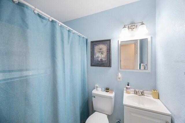 bathroom featuring curtained shower, vanity, and toilet