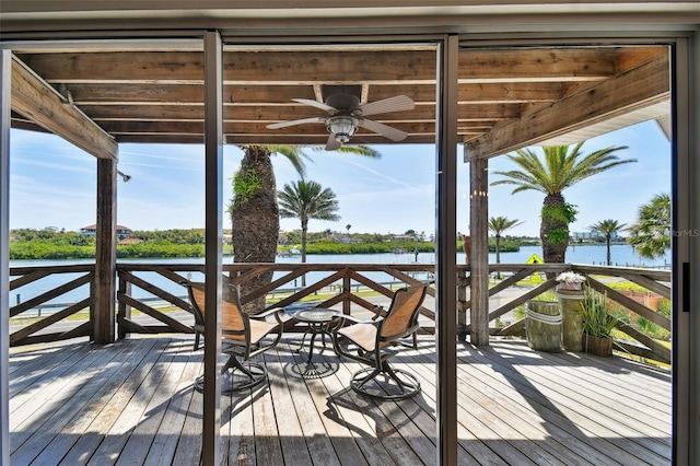 wooden deck with ceiling fan and a water view