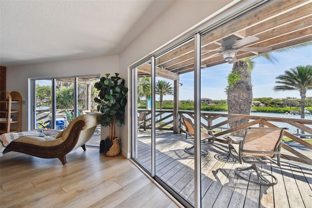 doorway featuring a water view, light hardwood / wood-style floors, ceiling fan, and a textured ceiling