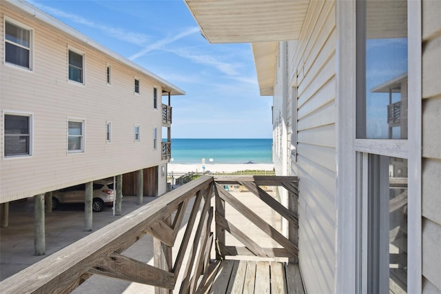 balcony with a water view and a view of the beach