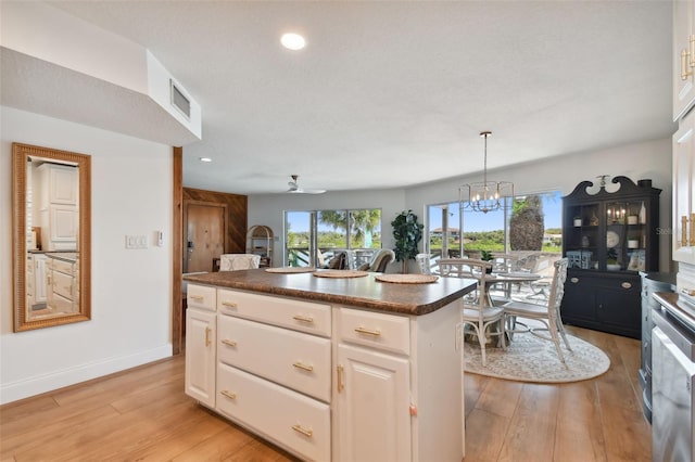 kitchen with hanging light fixtures, white cabinets, ceiling fan with notable chandelier, a kitchen island, and light wood-type flooring