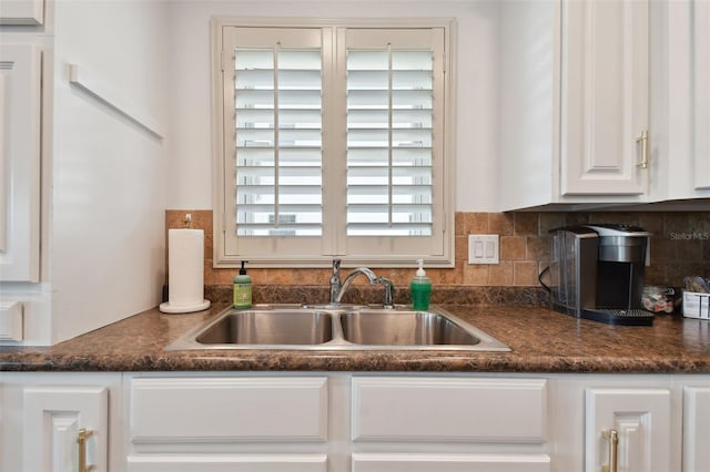 kitchen with decorative backsplash, white cabinetry, and sink