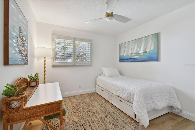 bedroom featuring ceiling fan, a textured ceiling, and wood-type flooring