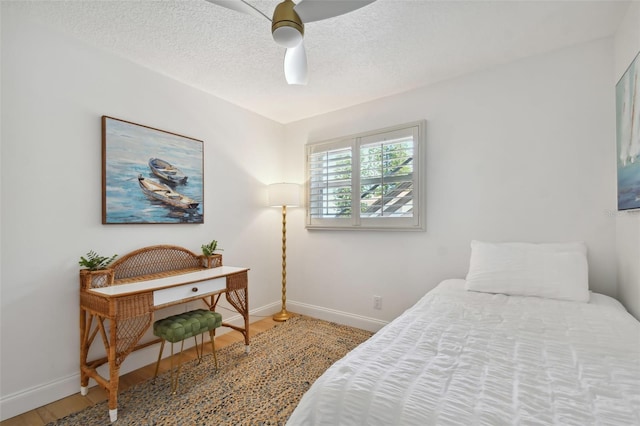 bedroom featuring ceiling fan, hardwood / wood-style flooring, and a textured ceiling