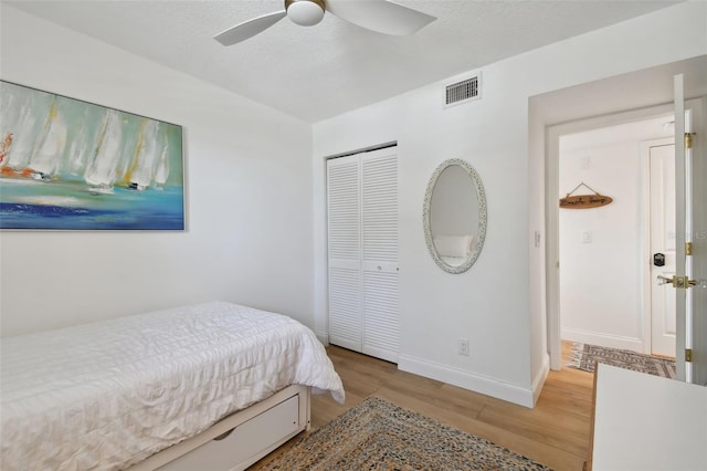 bedroom featuring light hardwood / wood-style floors, ceiling fan, and a closet