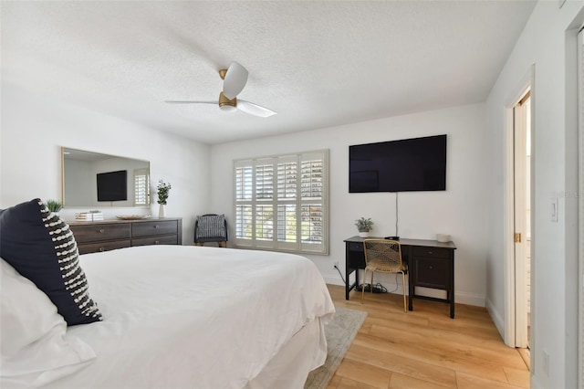 bedroom with a textured ceiling, ceiling fan, and light hardwood / wood-style flooring