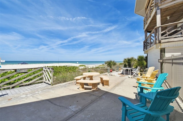 view of patio / terrace with a balcony, a water view, and a view of the beach