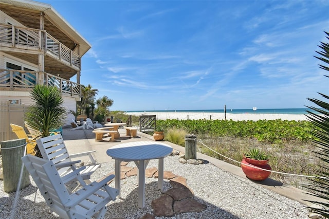 view of patio featuring a balcony, a water view, and a view of the beach