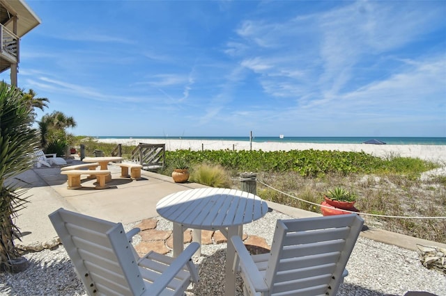 view of patio featuring a beach view, a water view, and an outdoor fire pit