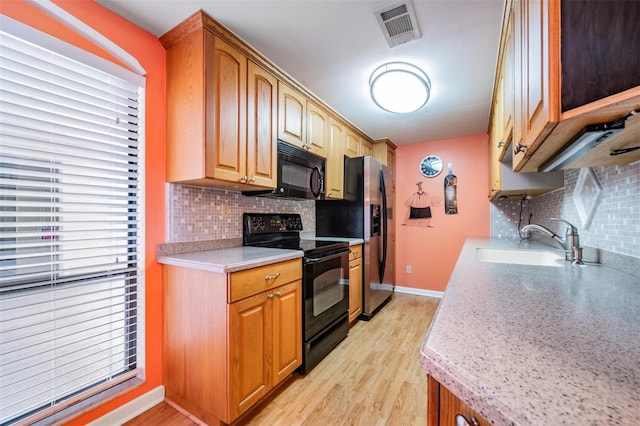 kitchen featuring black appliances, light hardwood / wood-style floors, tasteful backsplash, and sink