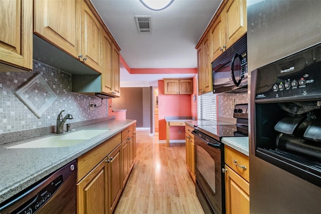 kitchen featuring decorative backsplash, light hardwood / wood-style floors, light stone counters, black appliances, and sink