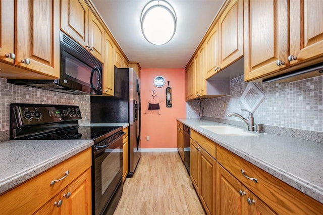 kitchen featuring black appliances, light hardwood / wood-style floors, sink, and tasteful backsplash