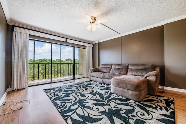 living room with ceiling fan, hardwood / wood-style flooring, ornamental molding, and a textured ceiling