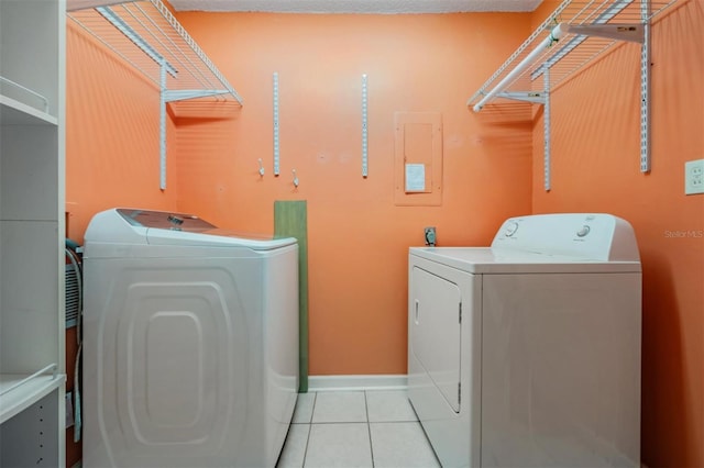 clothes washing area featuring electric panel, light tile patterned floors, and washing machine and dryer