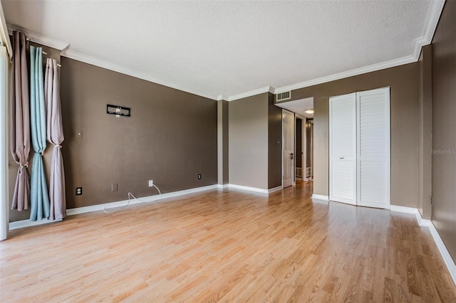 interior space with ornamental molding, light wood-type flooring, and a textured ceiling