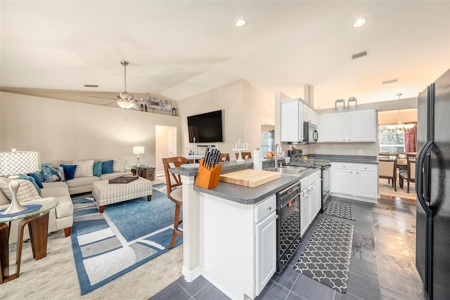 kitchen featuring lofted ceiling, a breakfast bar, white cabinetry, black appliances, and ceiling fan with notable chandelier