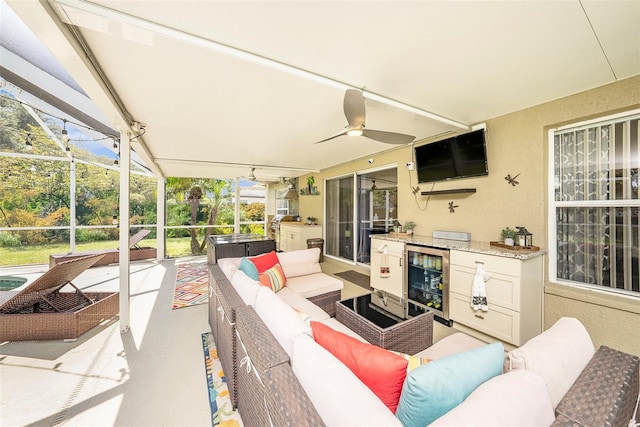 view of patio featuring ceiling fan, wine cooler, glass enclosure, and outdoor lounge area