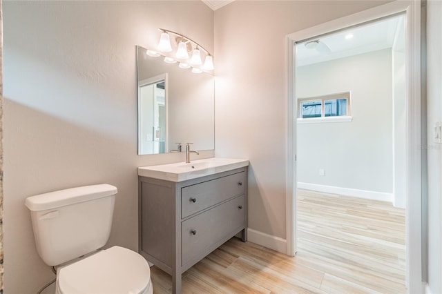 bathroom with crown molding, wood-type flooring, vanity, and toilet