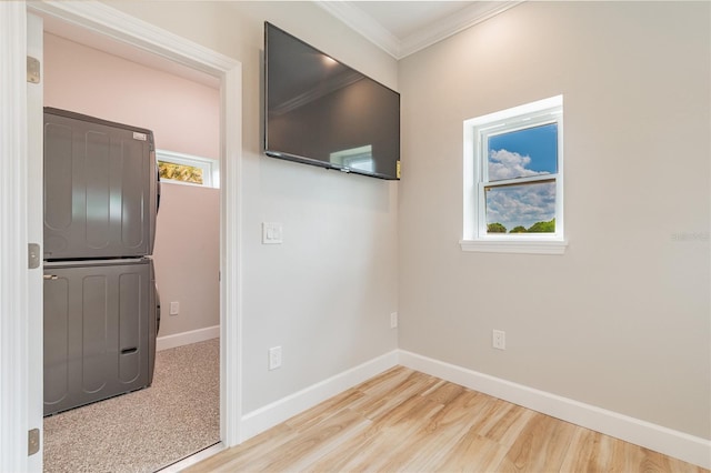 unfurnished room featuring wood-type flooring, stacked washer / dryer, and ornamental molding