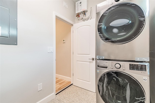 laundry area with stacked washer / drying machine and electric panel