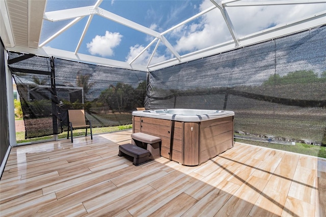 deck featuring a hot tub and glass enclosure