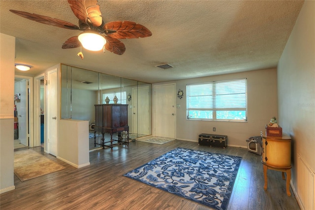 interior space with a textured ceiling, wood finished floors, visible vents, and baseboards