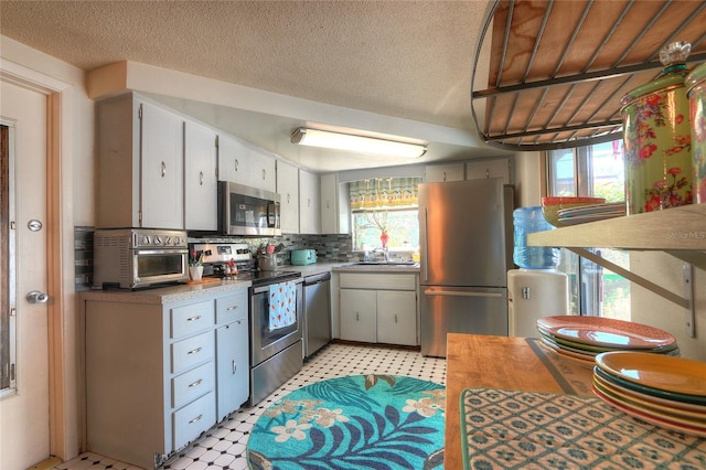 kitchen featuring appliances with stainless steel finishes, a healthy amount of sunlight, a sink, and light floors