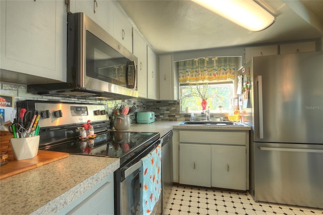 kitchen featuring a sink, light countertops, appliances with stainless steel finishes, decorative backsplash, and light floors