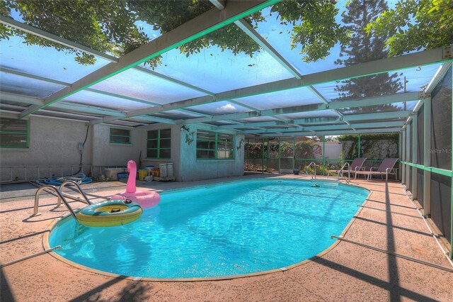 pool featuring glass enclosure, a patio area, and fence